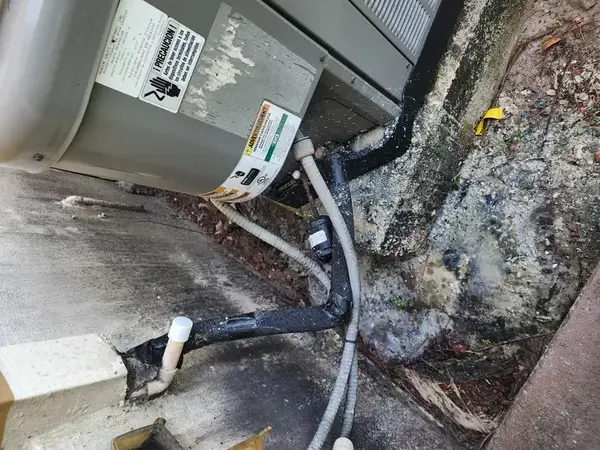 Clogged AC condensate drain line being cleaned by HVAC technician