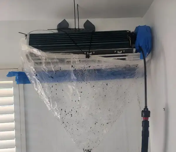 Mini split AC unit being deep cleaned with SpeedClean bib bag catching debris